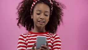 Focus pull of african american kid with smartphone isolated on pink
