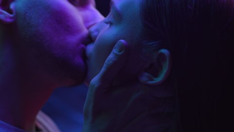 Two Lovers Kissing in Colourful UV Lighting of City Street. Intimacy of Couple in Multi-Colour or Ultra-Violet Filter Closeup. Modern Love and Relationship of Young Pair in Neon of Dark Room Indoors