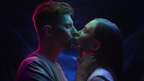 Two Lovers Kissing in Colourful Lighting of Dark Room. Intimacy of Pretty Couple in Multi-Colour or UV Filter Indoors. Young Love and Close Relationship of Modern Pair in Rainbow Neon of Urban Street