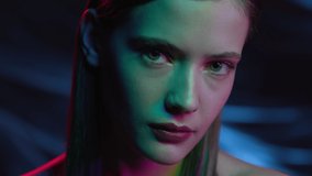 Portrait of Girl Looking at Camera in Colourful Filter. Multi-Colours in Neon Lighting of Dark Room. Futuristic Advertisement of Fashion with Young Woman. Lady Watching on Ultra-Violet Light of Night