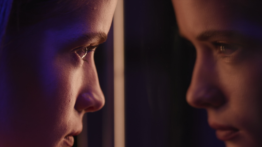 Woman Looking in Mirror Reflection. Make-Up on Calm Face of Young Girl in Retro-Wave Style of Neon Lighting. Multi-Colours of Night City or Glass Room of Club. Colourful Individuality of Charming Lady Royalty-Free Stock Footage #1048130152
