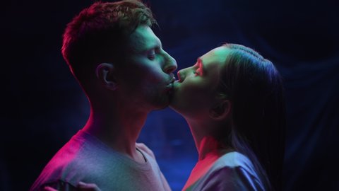 Two Lovers Kissing in Colourful UV Lighting of Urban Streets. Intimacy of Pretty Couple in Iridescent Multi-Color Filter of Dark Room. Modern Love of Young Pair in Rainbow Illumination of Neon Signs