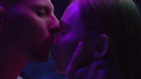 Two Lovers Kissing in Colourful UV Lighting of Dark Room Indoors. Intimacy of Pretty Couple in Multi-Colour or Ultra-Violet Filter Close-Up. Modern Love of Young Pair in Neon Shining of Urban Street