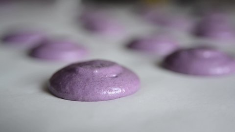 Preparation macaroons dough before baking in the oven. The process of cooking macaroons. French dessert. Colorful blueberry macaroons on parchment.