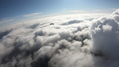 Four skydivers are flying in the sky, and falling in the white cloud.