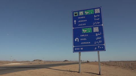 SAUDI ARABIA – DECEMBER 2019: Construction trucks drive past traffic sign on Jeddah to Jordan highway in Saudi Arabia
