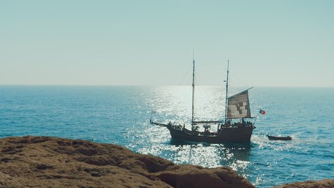 Slow-motion of pirate boat sailing near the beach on a sunny day. Large medieval ship on the sea.