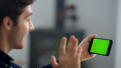 Closeup business man making video call on smartphone in slow motion. Close up of businessman making video chat on green screen mobile phone. Male professional waving hands after conference call.