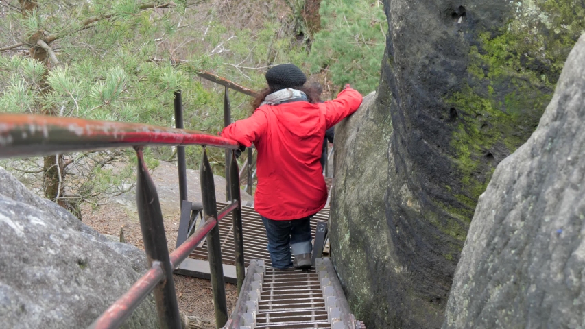 mature woman climbing down the stairs from the Schrammsteine in the Elbe Sandstone Mountains, Saxon Switzerland National Park, Germany, Travel and enjoying life to the fullest, exploring nature 
