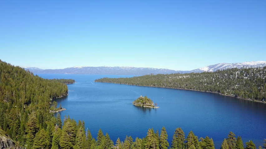 Aerial descending, Lake Tahoe Emerald Bay over forest of trees and water