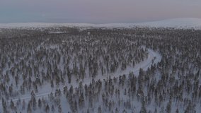 LAPLAND, FINLAND. Aerial drone shot of  snowy  Arctic Resort in the forest.  Arctic Circle winter drone video with ski resort on the background 