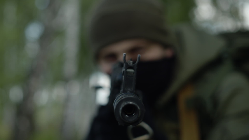 The focus from the machine gun is transferred to the soldier in the forest