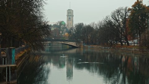 Left to right pan real time shot Isar river in the German city Munich. Busy traffic on the road.