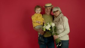 Cheerful grandparents posing with flowers and smiling kid