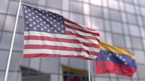 Flying flags of the USA and Venezuela in front of a modern skyscraper