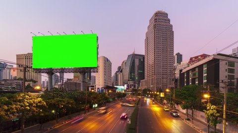 Time-lapse: Billboard with green screen and city traffic light background at day to night. 4K Resolution.