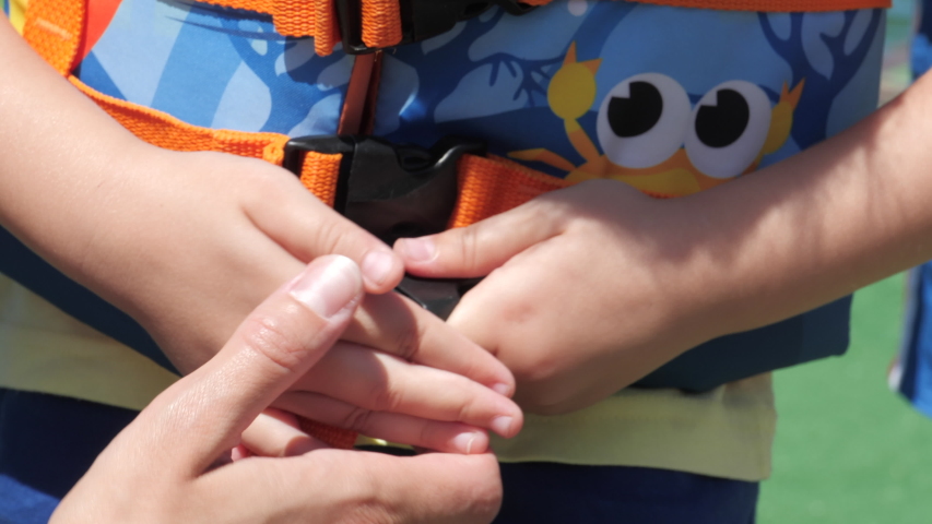 mom fastens the seat belt on the waistcoat that she is wearing on her daughter