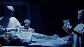 Team of Medical Surgeons use Futuristic Holographic Touchscreen Tablets to Examine Patient during Medical Procedure. Transparent Screens showing ECG and Medical Data Activity. Shot on RED Epic W. - Powered by Shutterstock - Get 15% off with code: PIKWIZARD15