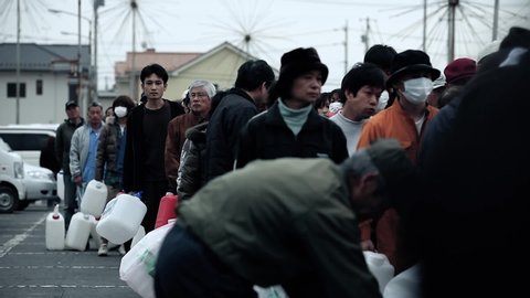 Fukushima, Japan - 03/11/2011 : queue of civil who wait for the distribution of drinkable water with empty bottles after the tsunami