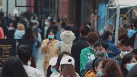 Chengdu, Sichuan/China-March 4th 2020:Crowd walking zebra crossing wear protective mask for protect Coronavirus, during  Covid 19 virus outbreak looking at phone at Taikoo Li commercial town