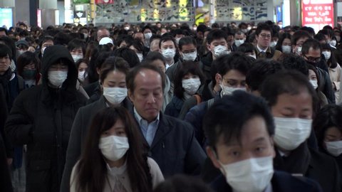 TOKYO, JAPAN -MARCH 2020 : Crowd of people walking at Shinagawa station in busy morning rush hour. Many commuters going to work. People wearing mask to protect from Coronavirus(COVID-19). Slow motion.