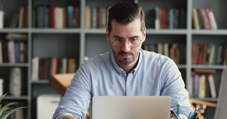 Thoughtful business man thinking of problem solution working on laptop. Serious doubtful male professional looking away at laptop considering market risks, making difficult decision sitting at desk Royalty-Free Stock Footage #1048239448
