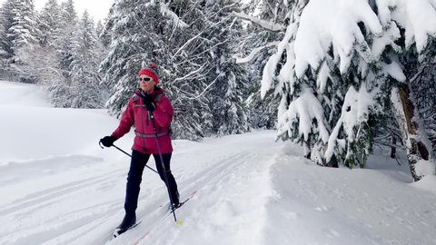 nice senior woman , crosscountry skiing in fresh fallen snow on a ski track in the Allgau Alps, Bavaria, Germany