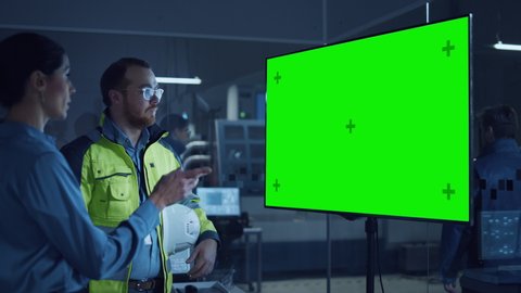 Office Meeting: Confident Female Project Manager to Chief Engineer, Watching Interactive Digital Whiteboard TV that Shows Green Screen Chroma Key Display. Modern Factory with Machinery. Slow Motion 