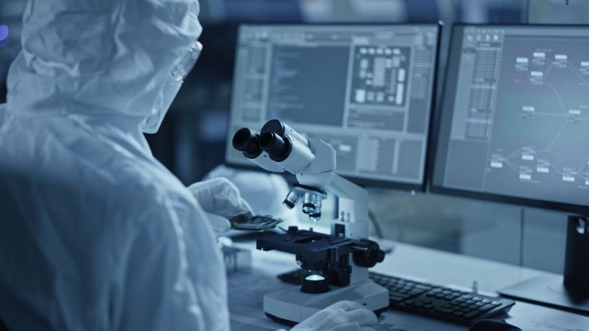 Research Factory Cleanroom: Engineer / Scientist wearing Coverall and Gloves Uses Microscope to Inspect Samples, Developing High Tech Modern Technology for Medical and Precision Electronics Industry | Shutterstock HD Video #1048253971