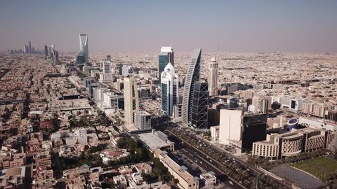 RIYADH, SAUDI ARABIA – DECEMBER 2019: Flying backwards on King Fahd Road along tall skyscrapers and commercial buildings in central Riyadh city in Saudi Arabia
