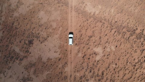 Aerial over off road 4x4 car driving along gravel trail path. Overhead on white offroad vehicle on desert Pamir Highway silk road travelling in Tajikistan,Asia. 4k drone flight.Top view perspective