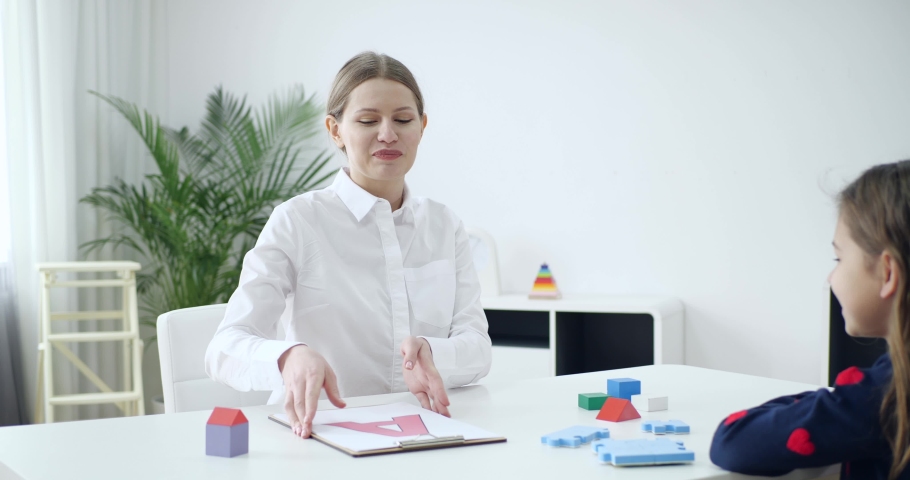 Speech therapist working with little girl in office