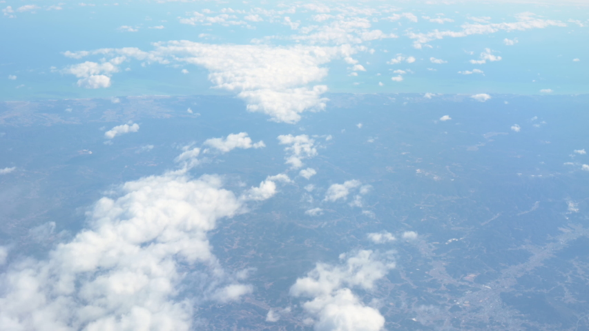 Footage of aerial view above clouds from airplane window with blue sky. view from the airplane window to the blue sky and white clouds. ravelling by air background. Royalty-Free Stock Footage #1048266088