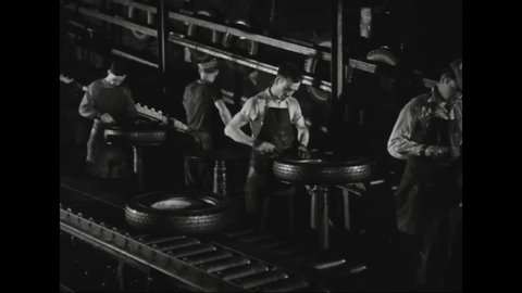 CIRCA 1931 - workers manufacture rubber tires in an automobile factory.