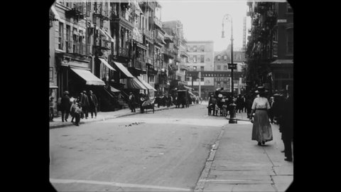 CIRCA 1911 - Pedestrians walk, and carriages and trolleys ride through the city streets of Manhattan.
