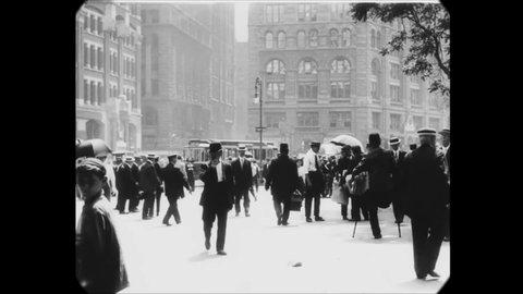CIRCA 1911 - Pedestrians walk and carriages ride through the city streets of Manhattan, New York City.