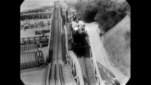 CIRCA 1904 - Men and women enjoy amusement park rides in Folkestone, Kent, England, with the camera mounted on front of a roller coaster car.