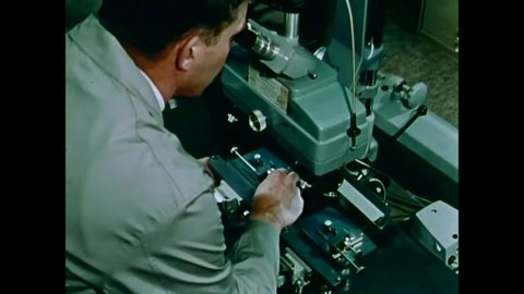 CIRCA 1970 - An examiner looks at the markings on test cartridge cases and bullets under a microscope in a FBI Identification Unit Laboratory.