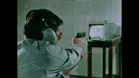 CIRCA 1970 - An examiner fires test shots from a pistol into a box filled with cotton and padding in an FBI Laboratory.