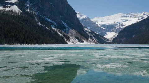 4K Time lapse pan shot of Lake Louise in spring with broken ice on the surface. Lake Louise is one the most visited lakes at Banff National Park, Alberta, Canada.