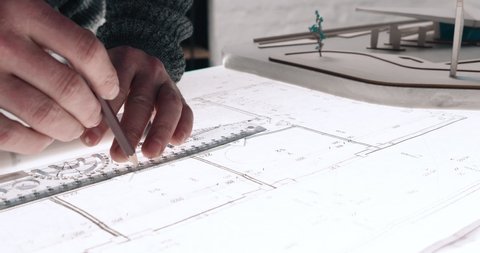 Close up of Man’s hands drawing lines on the Large Format Paper at Modern Office. Architect using Ruler and Pencil to make Blueprints on the Paper. Having very Responsible Job. Great work.