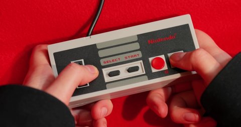 BUDAPEST, HUNGARY - FEBRUARY 17, 2018: Playing the classic Nintendo NES console from the 80s, controller closeup.
