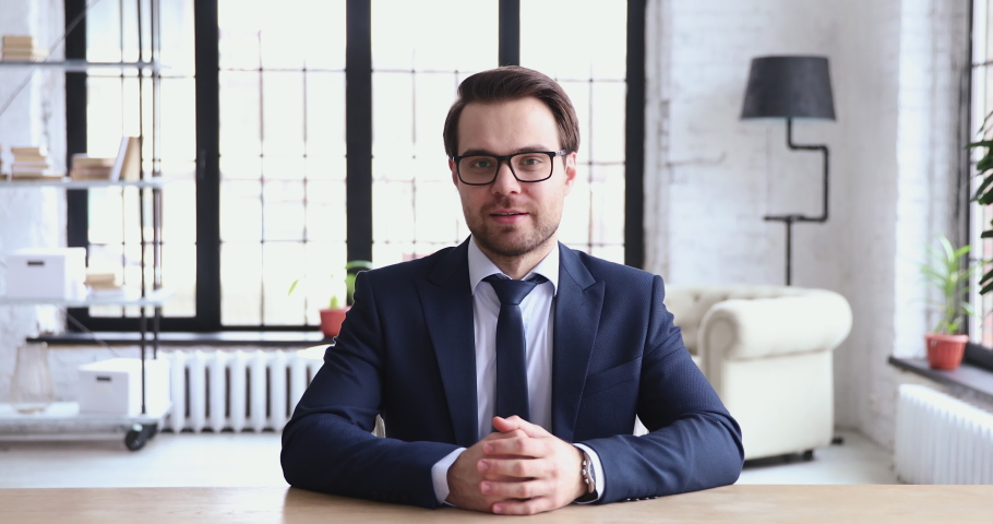 Young ceo speaking to camera recording business video presentation. Confident businessman wearing suit and tie looking talking to web cam streaming webcast training, doing conference call in office. | Shutterstock HD Video #1048284727