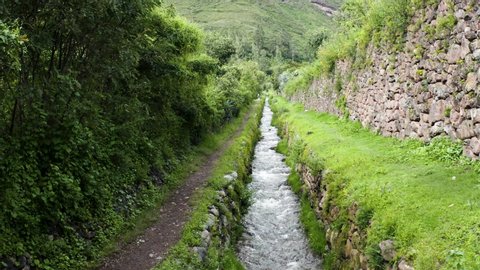 Aerial shot of creek next to a walking path in Urubamba, sacred valley of the incas located in Cusco, Perú.