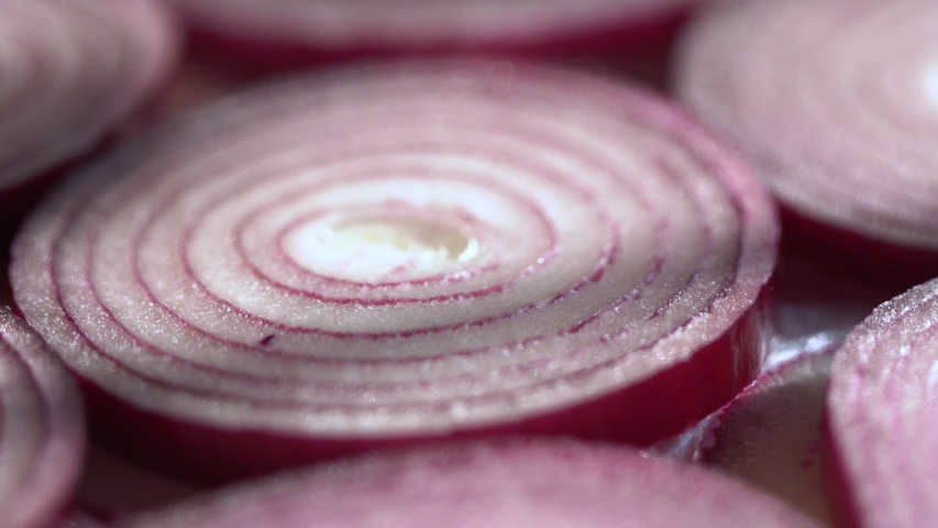 Sliced red onion rings rotating on white in 4K. Closeup top view of healthy food background with vegetable of rich vitamin.