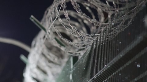 Perimeter security fencing system, razor wire fence with lighting at night, welded wire mesh fence line.