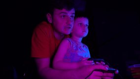 Father teaches his son to play retro console. Neon lighting
