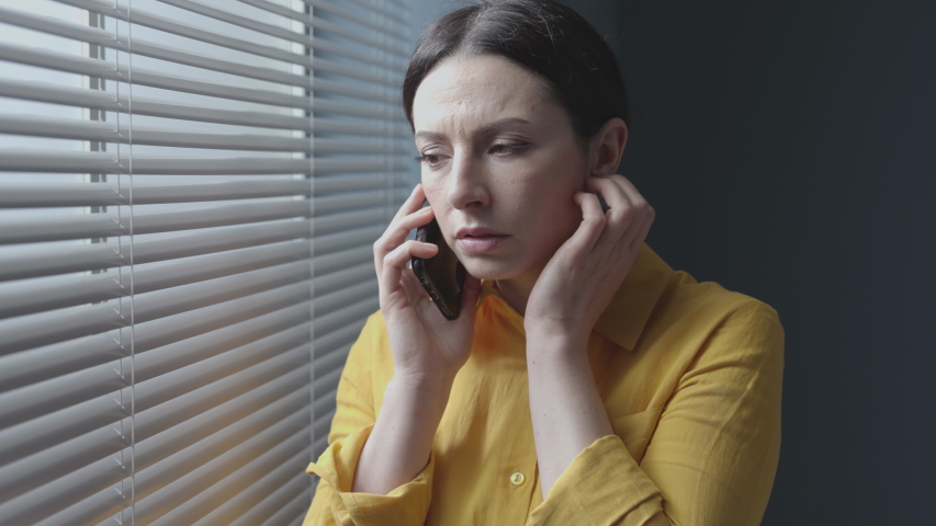 Woman receiving bad news on the phone, she is shocked and panicked