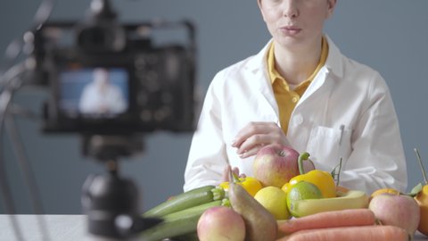 Professional nutritionist shooting a video for her channel, she is sitting in front of the camera and talking about healthy diet