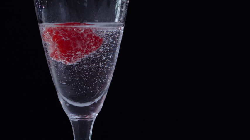 Frozen Raspberry drifting inside glass of clear water. filmed in 240fps superslowmotion